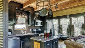A modern kitchen with dark cabinetry, stainless steel appliances, and a wooden ceiling. - Dancing Dragonfly (Sevierville)