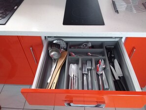 Eine Schublade mit Küchenutensilien und einer schwarzen Schneidebrett.