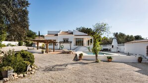 Ein modernes Haus mit Schwimmbad, Sitzgelegenheiten im Freien und einer Pergola.
