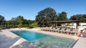 Ein Schwimmbecken mit klarem Wasser, umgeben von Liegestühlen und einer Pergola.