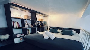 Quarto moderno com cama grande, estante embutida e um cantinho aconchegante para leitura.