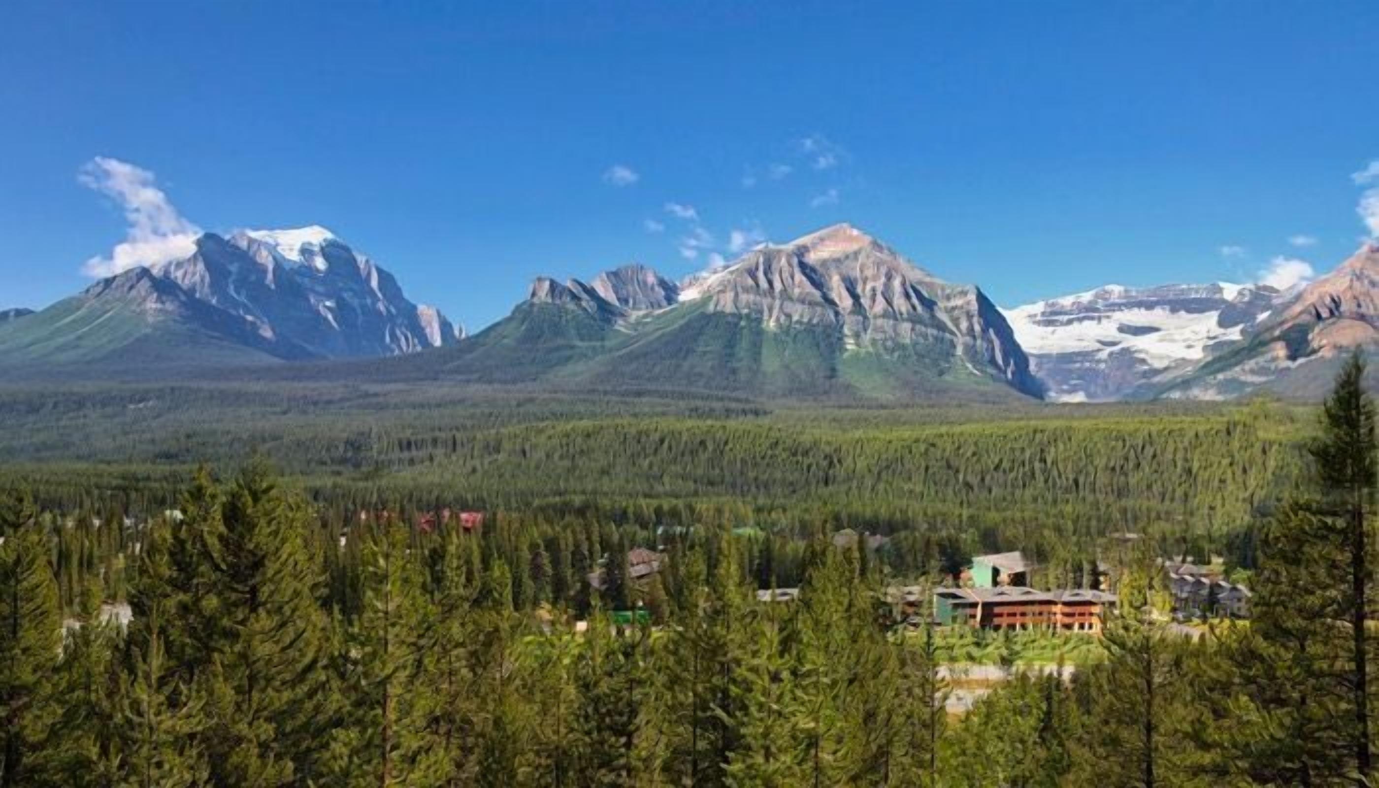 A lodge with a view of snow-capped mountains and dense forest.