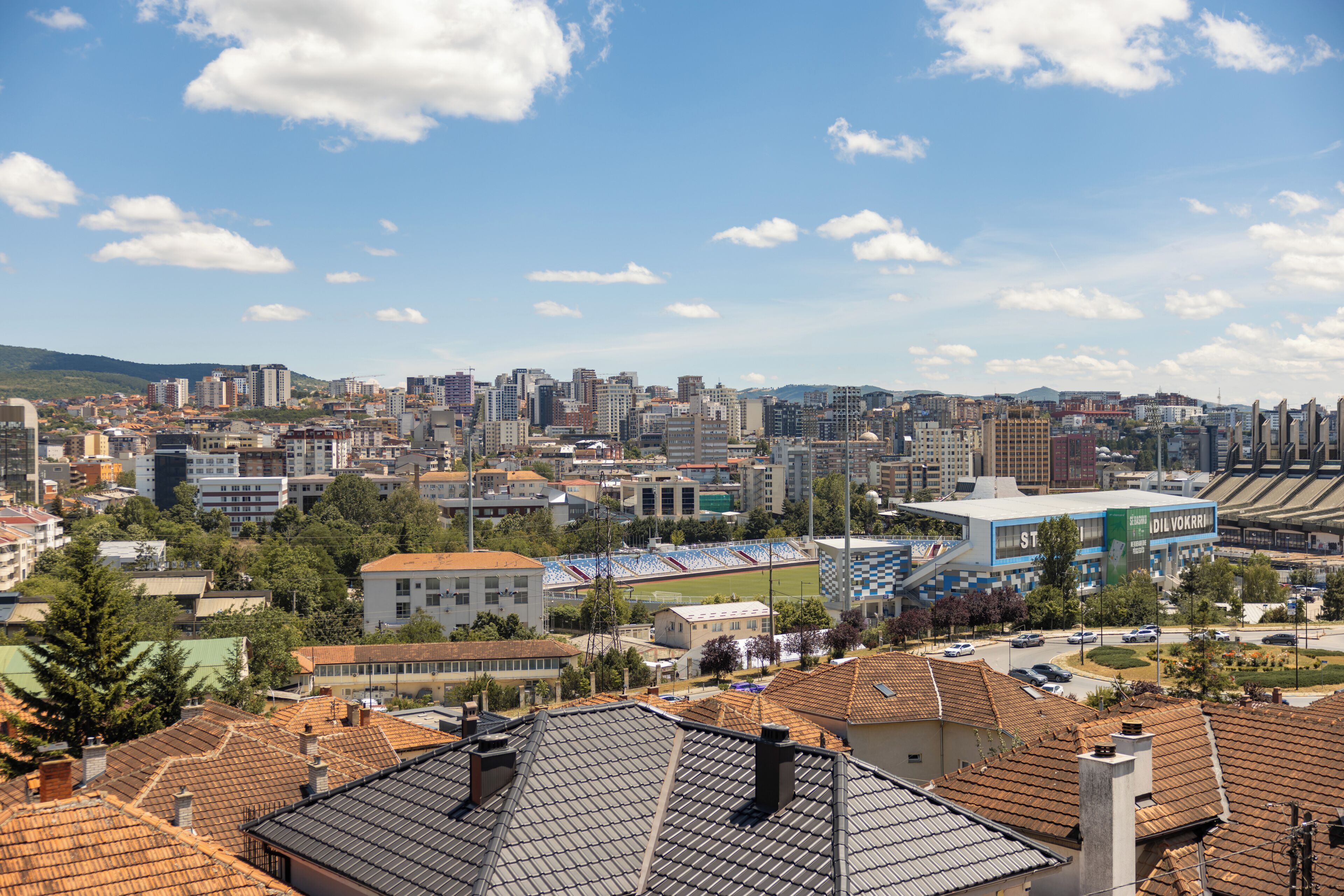 A cityscape with a stadium, buildings, and a clear sky.