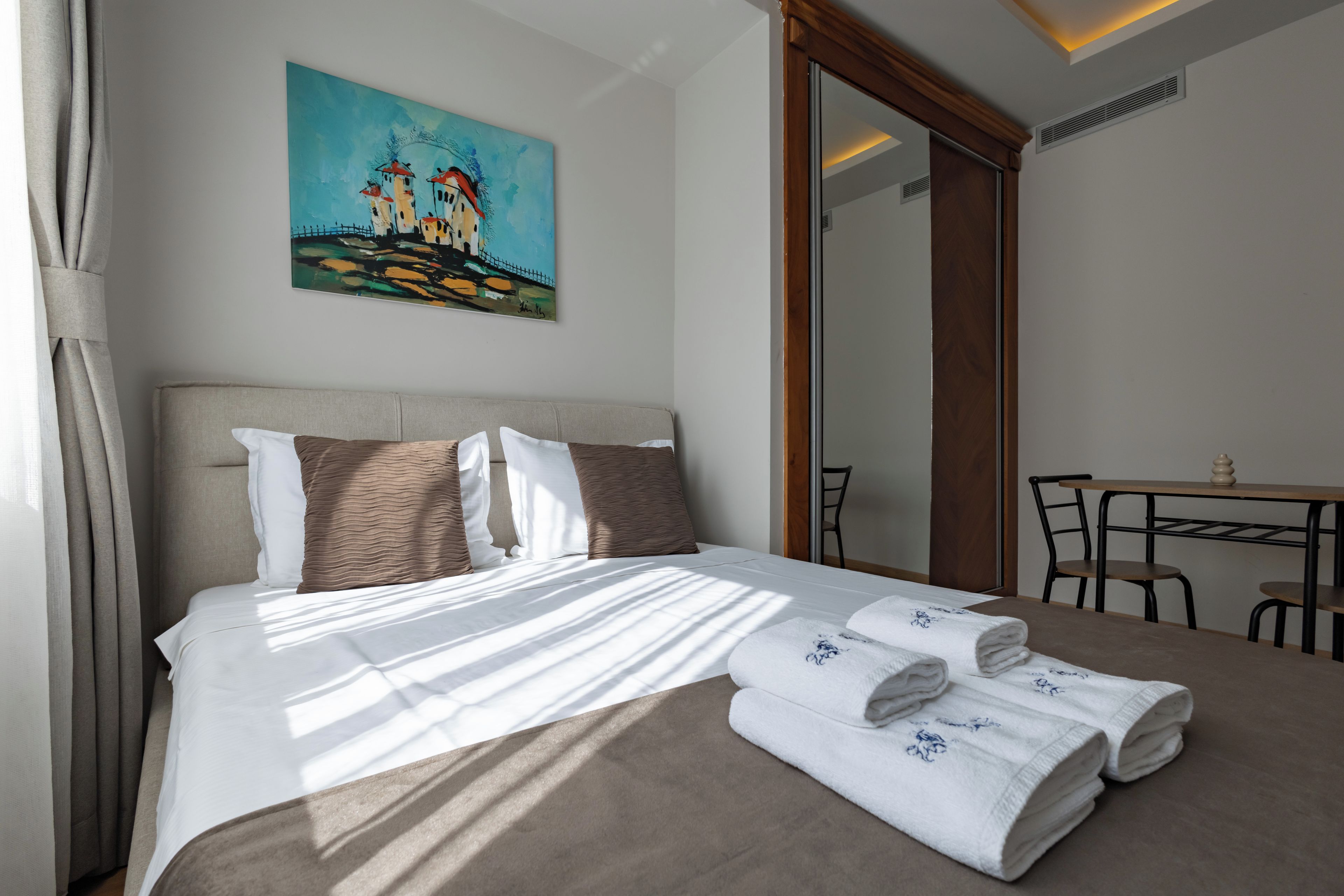 Una habitación de hotel con una cama, un cuadro en la pared, un escritorio y una silla.