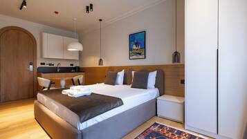 Een moderne hotelkamer met een groot bed, een kitchenette en een eettafel.
