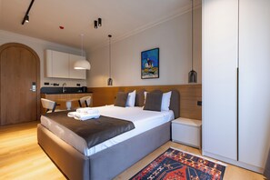 A modern hotel room with a large bed, a small kitchen area, and a dining table. - PRI ApartHotel (Pristina)