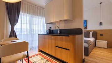 A compact, modern room with a kitchenette, a dining area, and a bed.