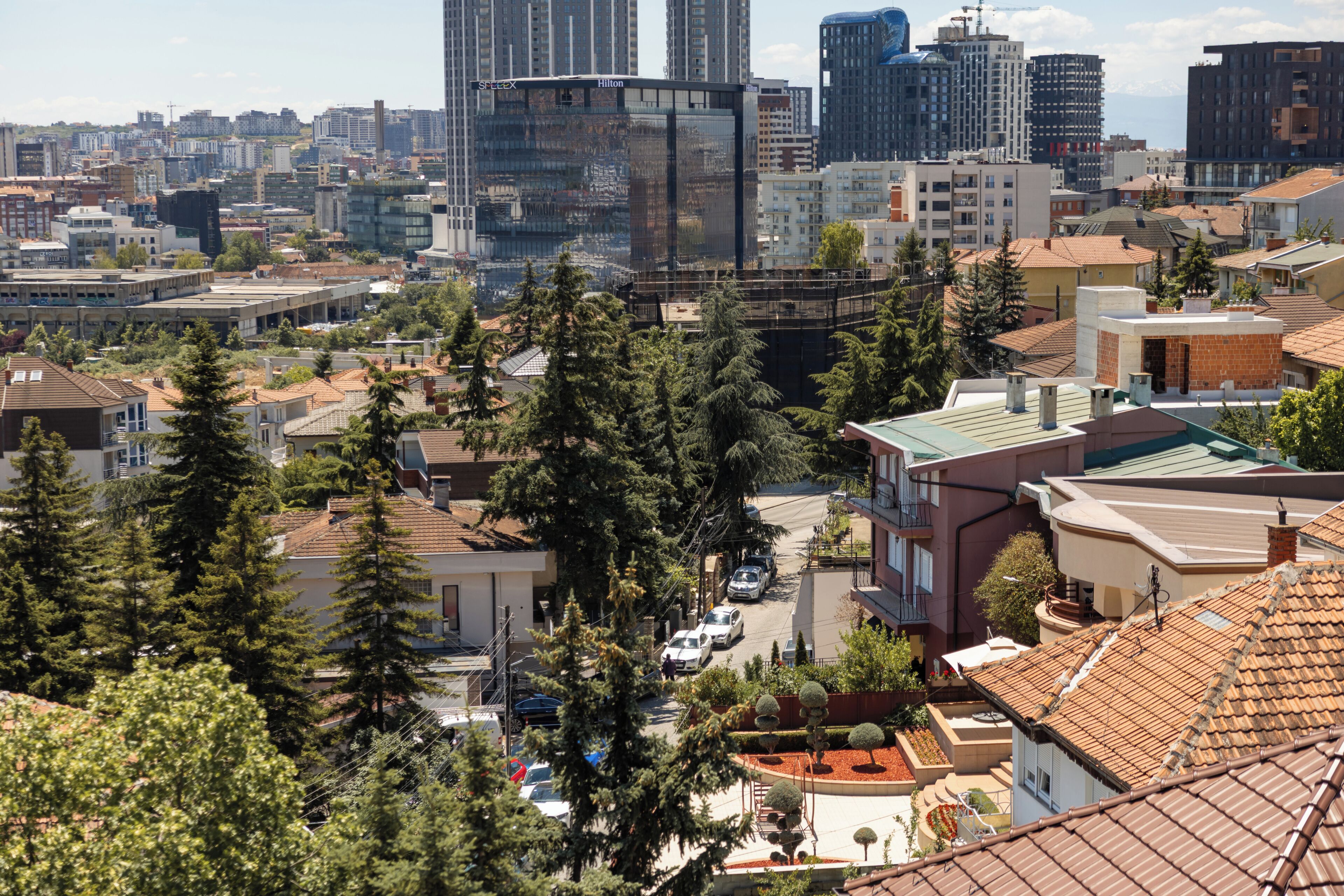 Un paysage urbain avec des bâtiments modernes et traditionnels, un mélange de structures résidentielles et commerciales, et un ciel dégagé.