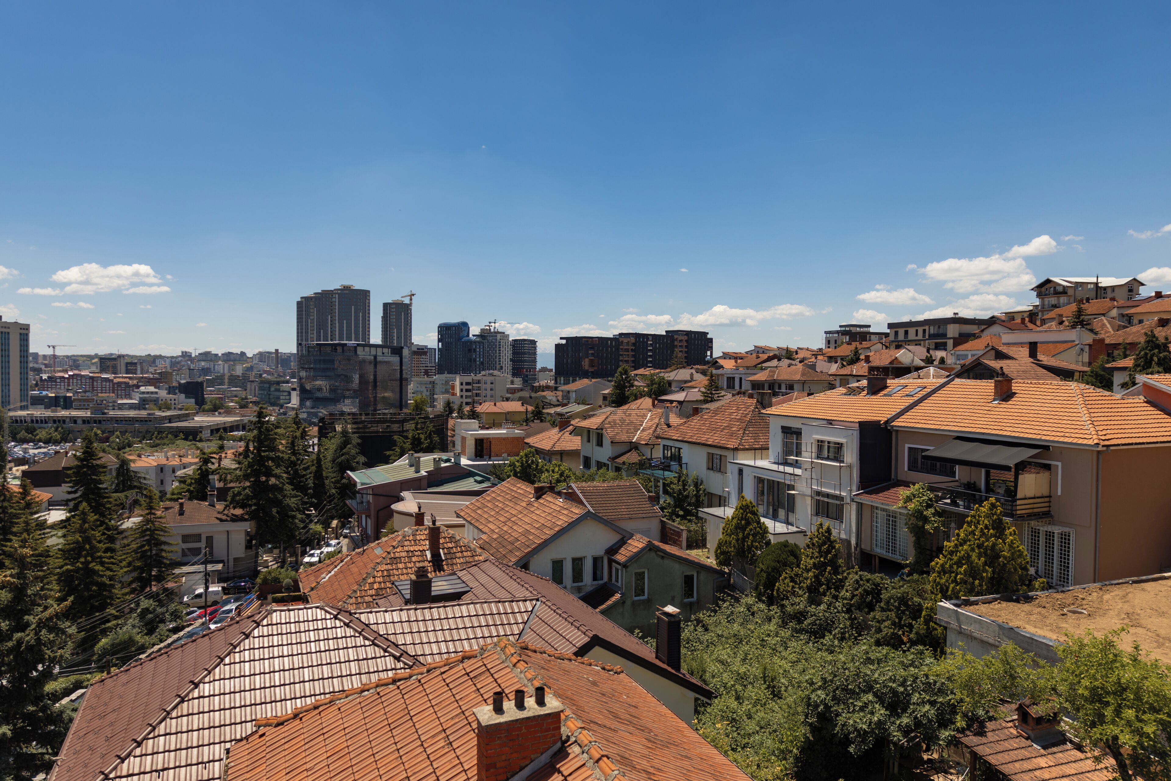 A residential area with various building styles, including modern and traditional houses, under a clear sky.