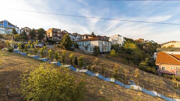 A residential area with multiple two-story houses, a staircase leading up a hill, and a clear sky.