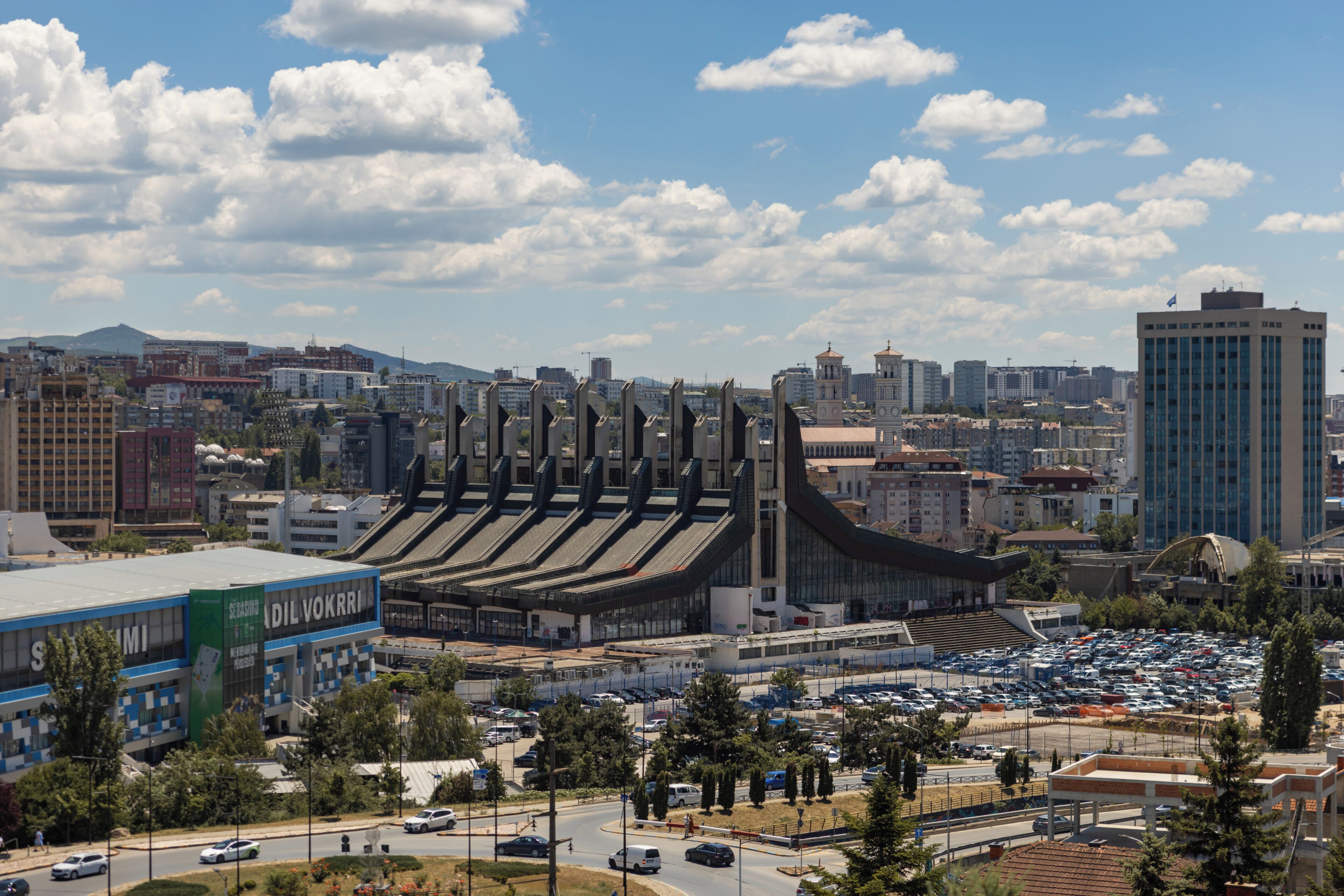 Un stade doté de plusieurs niveaux de gradins, entouré de bâtiments urbains et d’un parking.
