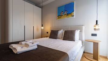 A bedroom with a bed, a painting, a round side table, and a wardrobe.