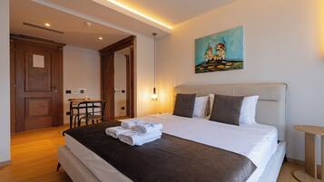 A hotel room with a bed, a painting, a desk, and a chair.