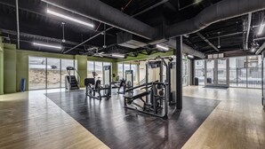 Een sportschool met trainingsapparatuur, grote ramen en een hoge plafond.