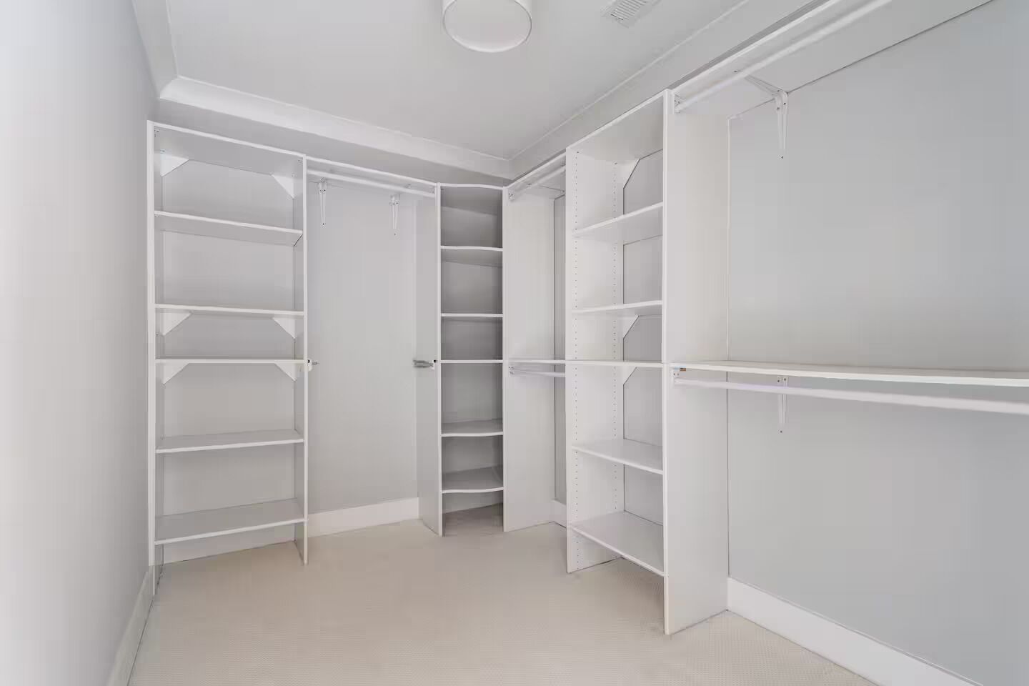 Un dressing spacieux, doté de nombreuses étagères et d’un grand espace pour suspendre les vêtements, avec un intérieur épuré de couleur blanche et un sol carrelé.