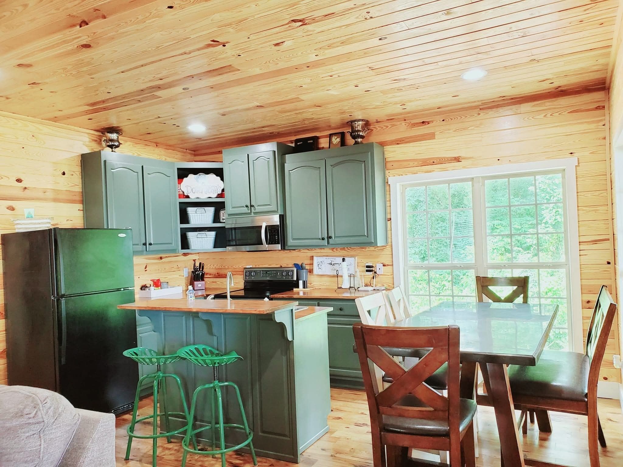 A compact kitchen with wooden cabinets, a refrigerator, and a dining area with a table and chairs.