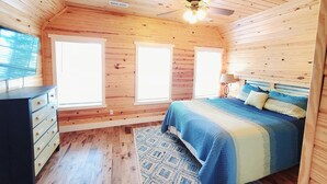 A wooden cabin bedroom with a bed, dresser, and ceiling fan. - Dora Jean's Lake Front Fishing Cabin w/ boathouse, on Lake Guntersville Sleeps12 (Scottsboro)