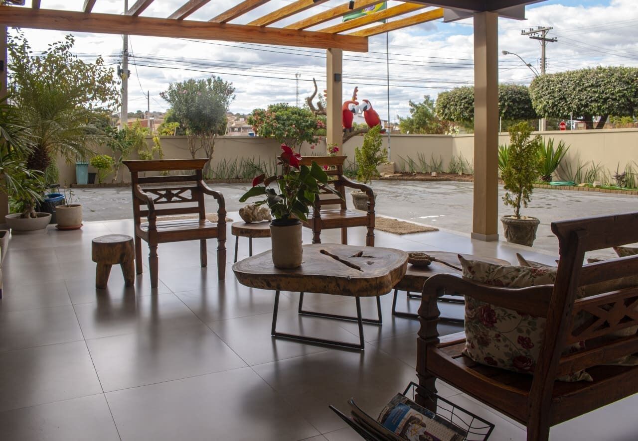 An outdoor patio with wooden furniture, potted plants, and a view of the street.