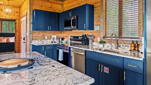 A modern kitchen with blue cabinets, stainless steel appliances, and a marble countertop. - Luxury Foliage Mtn Escape: Indoor Pool + Theater (Sevierville)