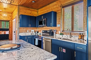 A modern kitchen with blue cabinets, stainless steel appliances, and a marble countertop. - Luxury Smoky Mtn Escape: Indoor Pool + Theater (Sevierville)