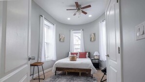 Una camera da letto con un letto, una ventola a soffitto, una finestra e una porta.