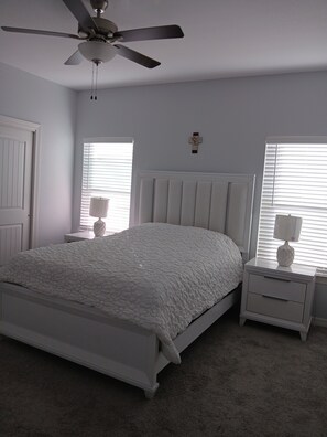 A bedroom with a white bed, a ceiling fan, two bedside tables with lamps, and a window with blinds. - Comfortable House in Westside of El Paso Texas (Canutillo)