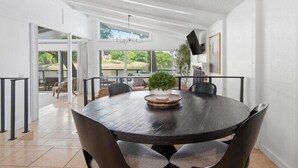 A modern dining area with a round table, chairs, a chandelier, and a view of the outdoors. - Lakefront Luxury w/ Dock, Great Location! (Vinita)
