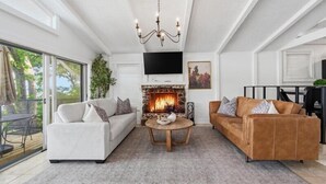 A modern living room with a fireplace, two sofas, a coffee table, and a chandelier. - Lakefront Luxury w/ Dock, Great Location! (Vinita)