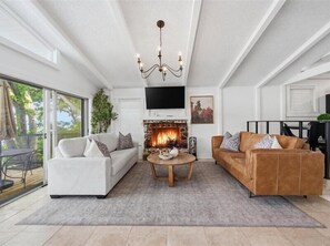 Una sala de estar moderna con chimenea, dos sofás, una mesa de centro y una araña.