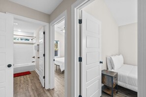 Ein Schlafzimmer mit Bett, Nachttisch und Blick auf ein Badezimmer mit Badewanne.