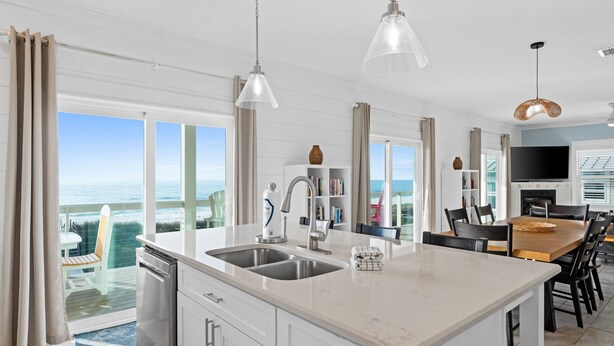 A modern kitchen with a large island, a dining area, and a view of the ocean. - Seaside Seaesta- Gulf-front views and private pool (Port St. Joe)