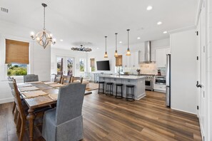 A spacious kitchen with a central island, wooden flooring, and modern lighting fixtures. - The Salty Bear- Cape San Blas, Community Pool, Family friendly! (Port St. Joe)
