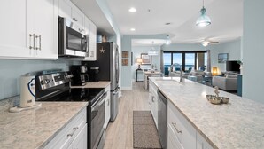 A modern kitchen with white cabinets, stainless steel appliances, and a marble countertop. - Club SeaLaVie- Family friendly, community pool, wifi (Mexico Beach)
