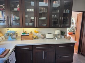 A kitchen with dark wooden cabinets, a countertop with a mixer, toaster, and coffee maker. - Pristine Stunning Home - Sunset Park Santa Monica (Santa Monica)