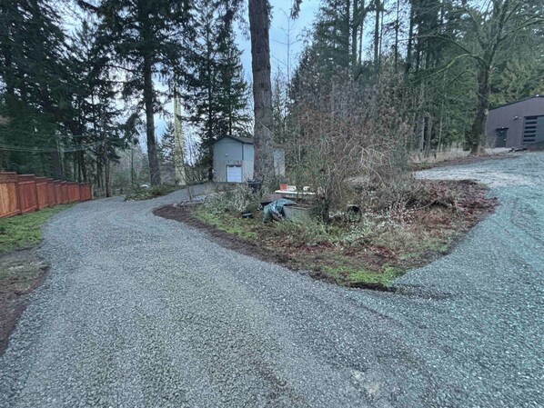 Une allée de gravier mène à un petit bâtiment entouré d’arbres.