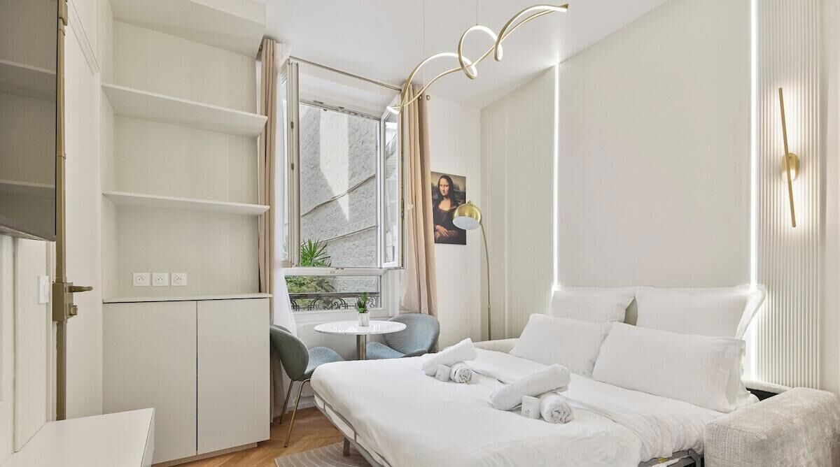 Une chambre d’hôtel moderne, équipée d’un lit, d’un bureau et d’une fenêtre avec des rideaux.