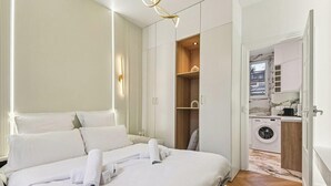 A hotel room with a bed, a wardrobe, a washing machine, and a small kitchen area. - Charmant studio Levallois-Perret proche de Paris (Levallois-Perret)