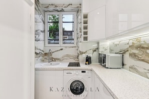 Eine kleine Küche mit Einbauwaschmaschine, Fenster und Mikrowelle.