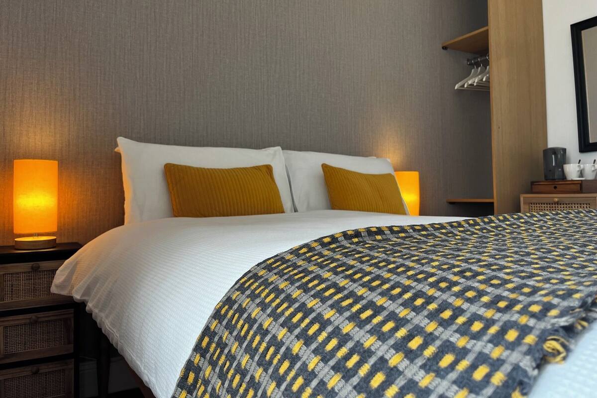 Una habitación de hotel con una cama, dos lámparas de noche, un armario y un espejo.