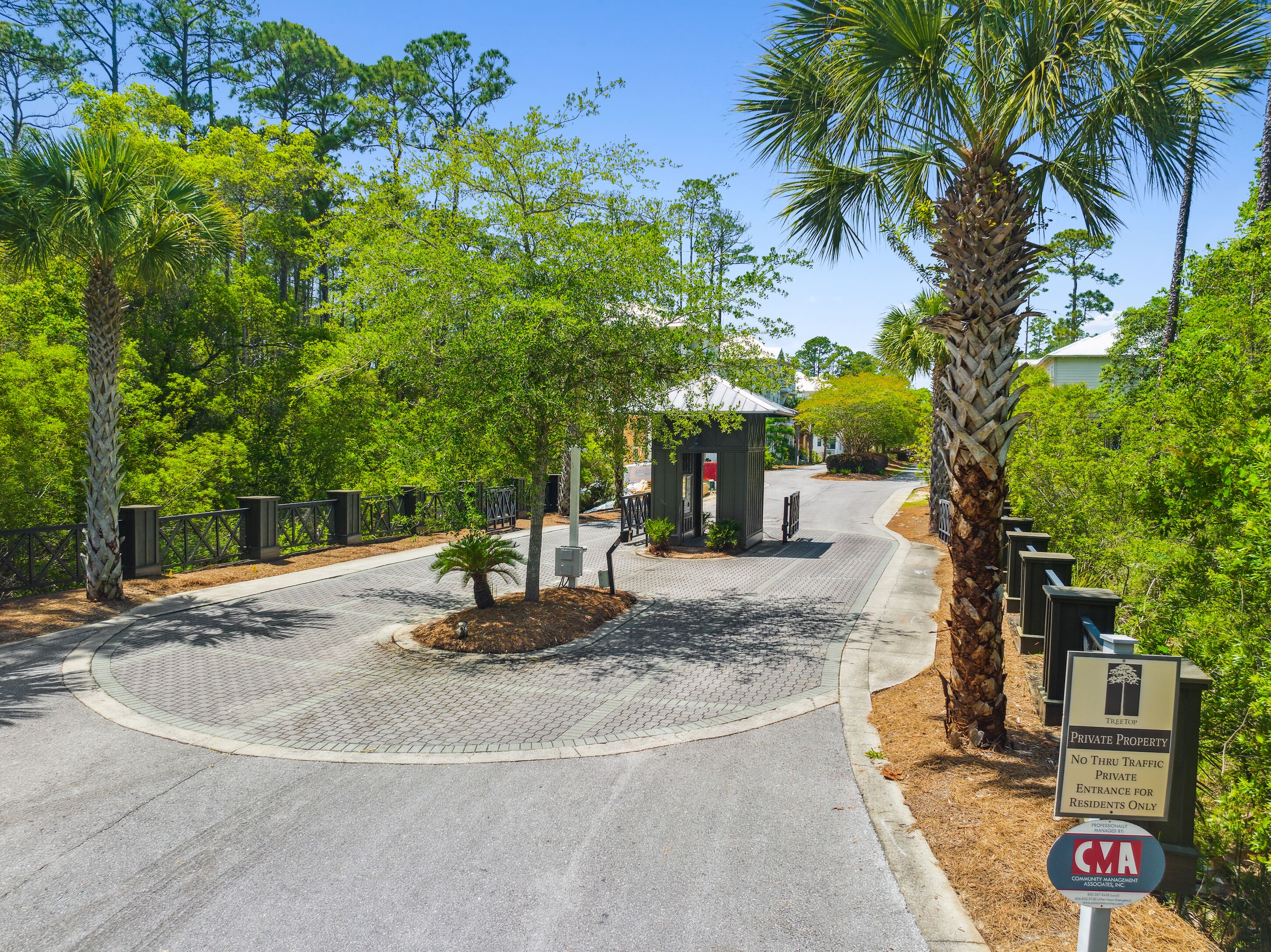 A gated entrance to a private property with a paved driveway and a sign indicating no thru traffic.