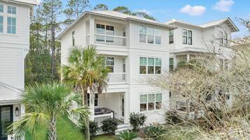 A multi-story residential building with a porch and a small garden area.
