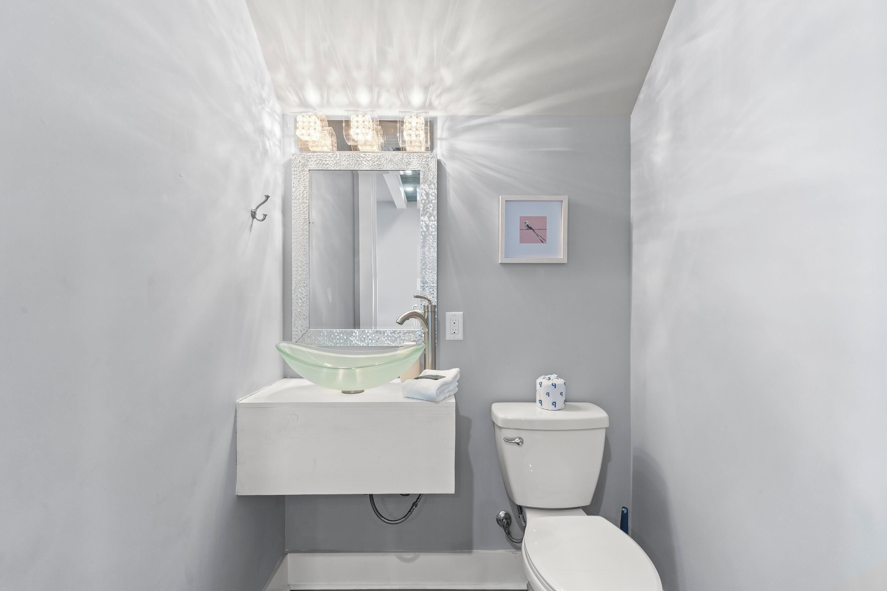 Une salle de bain moderne avec un lavabo blanc, un grand miroir et des toilettes.