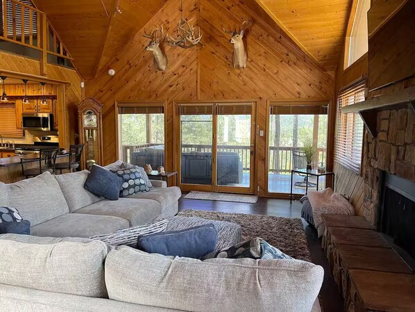 A spacious living room with a large gray sectional sofa, a fireplace, and a stone accent wall. - Circle C on Timberline (Ruidoso)