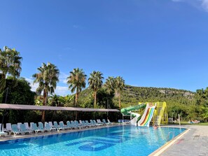 A swimming pool with lounge chairs and a water slide. - Pera Aura Resort Hotel & Spa - All Inclusive (Kemer)