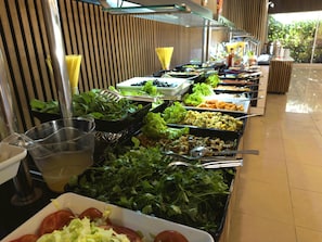 Buffet com diversas opções de comida, incluindo saladas, vegetais e outros pratos.