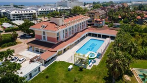 A hotel with a swimming pool, multiple buildings, and a view of the sea. - Pera Aura Resort Hotel & Spa - All Inclusive (Kemer)