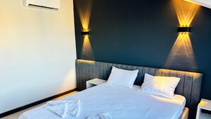 A hotel room with a bed, two bedside tables, an air conditioning unit, and wall-mounted lighting. - Pera Aura Resort Hotel & Spa - All Inclusive (Kemer)