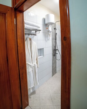 Ein Badezimmer mit Dusche, einem Handtuchhalter und weißen Handtüchern sowie einem Holztürrahmen.