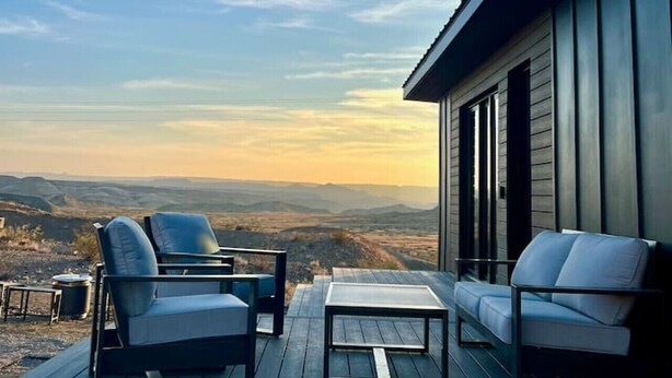 Een terras met twee stoelen en een tafel, met uitzicht op een mooi landschap.