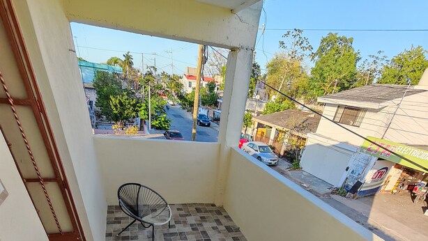 A balcony with tiled flooring and two wicker chairs. - Limestone House Apartment (Mérida)